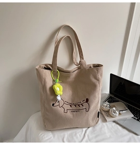Detalle del bolso tote de pana marrón claro con bordado de perro salchicha y colgante de flor