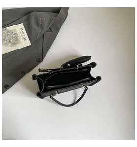 Detail view of black faux fur shoulder bag with chain strap and mini pouch on suit background