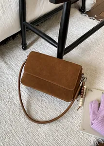 Detailed macro view of a brown suede handbag with wooden bead fringe decoration