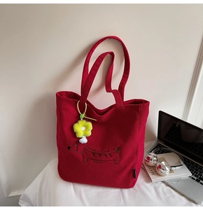 Detalle del bolso tote de pana roja con bordado de perro salchicha y colgante floral