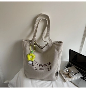 Detalle del perro salchicha bordado en bolso tote de pana beige con charm de flor
