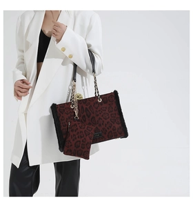 Detail of red leopard print tote with faux fur trim and gold chain handle on a model