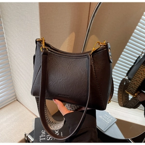 Detalle de bolso hobo de cuero negro con correa tejida y herrajes dorados elegantes