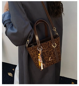 Detail of leopard print tote bag featuring a gold letter L charm and beaded strap