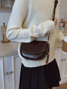 Dunkelbraune Vintage-Satteltasche aus glänzendem Leder, getragen von einem Model