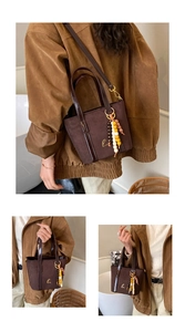 Detail of brown suede handbag with bead tassels, patent leather trim and long strap