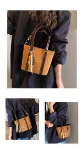 Detail of vintage tote bag with gold logo, wooden bead charm and brown matte leather