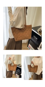 Detail view of brown quilted tote bag with circular metal handles and chain strap