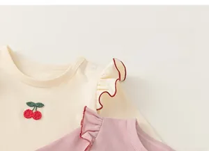 Detail of baby cotton long sleeve shirts featuring cherry embroidery and ruffle collar edges