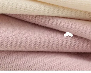 Close-up of soft knitted fabric with neat plain stitch patterns in beige and light pink