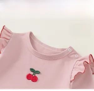 Macro detail of classic round neck and cherry embroidery on pink long sleeve baby shirt