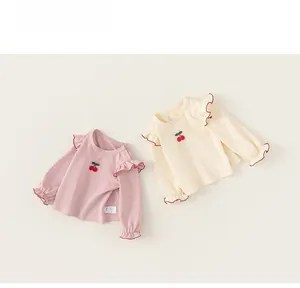 Detail of baby knit top with cherry embroidery, ruffle shoulders and snap buttons