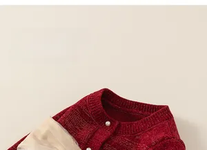 Dettaglio del cardigan in maglia rossa da bambina con bottoni di perla e fiocchi di seta