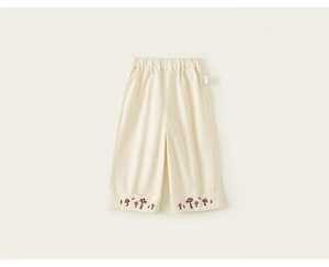 Dettaglio dei pantaloni ampi color crema per neonati con ricamo a fungo e vita elastica