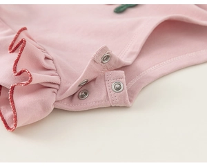 Detail of pink cotton baby romper crotch with three silver metal snap buttons and ruffle trim