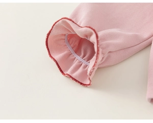 Detailed macro view of pink sleeve cuffs with red stitching and elastic ruffle design