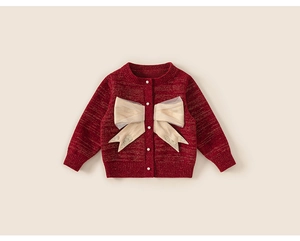 Dettaglio del cardigan festivo rosso a maglia con fiocco dorato e bottoni di perle