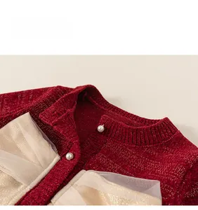 Dettaglio del cardigan in maglia rossa con filo dorato, bottoni di perle e fiocchi