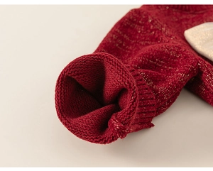 Macro dei polsini di un cardigan rosso con fili dorati e trama a maglia spessa