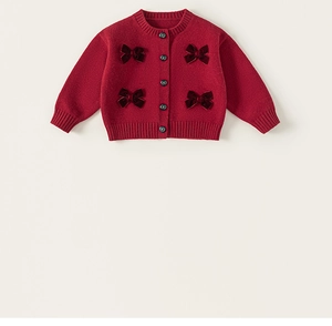 Dettaglio del cardigan rosso da bambina con fiocchi di velluto e bottoni vintage