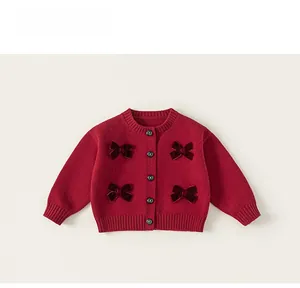 Dettaglio del cardigan in maglia rossa con fiocchi di velluto e bottoni rotondi