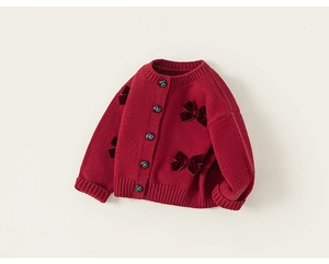 Dettaglio del cardigan in maglia rossa per bambina con fiocchi in velluto