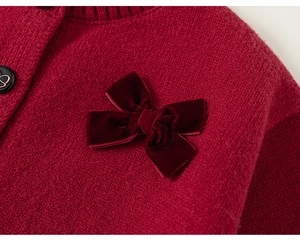 Dettaglio macro del cardigan rosso a maglia con fiocco di velluto e bottone nero