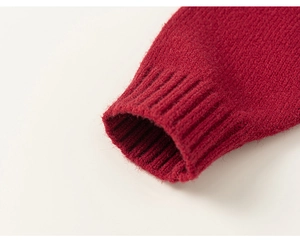 Dettaglio della manica di un maglione rosso a maglia con trama fine e polsini a coste