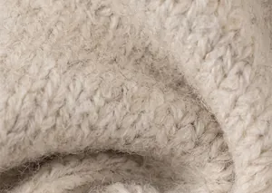 Detailopname van beige gebreide stof met zachte wolstructuur en grove steken