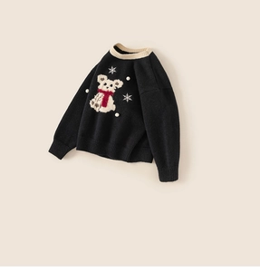 Detail of children's black sweater featuring a plush bear with red scarf and snowflakes