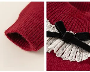 Dettaglio di maglione rosso con polsini a coste e fiocco in velluto nero con pizzo bianco