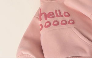 Close-up of pink girls' hoodie with hello print and soft kangaroo pocket detail