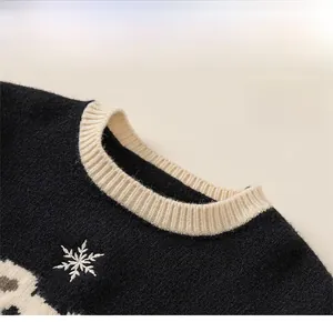 Close-up of winter knit sweater featuring white snowflake embroidery and contrast rib collar