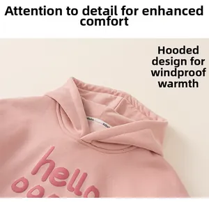 Macro detail of kids pink hoodie showing soft fabric texture and embossed hello print
