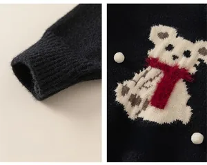Detail of children's knit sweater featuring a plush polar bear patch and ribbed cuffs
