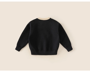 Detail of child knit sweater with ribbed cream collar and warm black knit texture