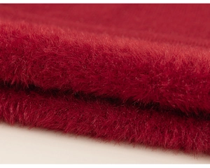 Dettaglio del tessuto a maglia peluche rosso scuro che mostra la texture morbida e calda