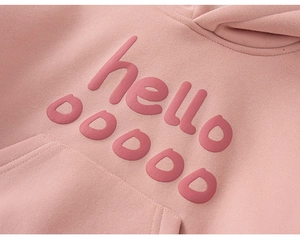 Close-up of pink girls hoodie featuring 3D puff print lettering and soft knit texture