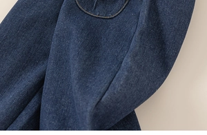 Détail de denim indigo avec surpiqûres denses et texture sergée pour pantalon enfant