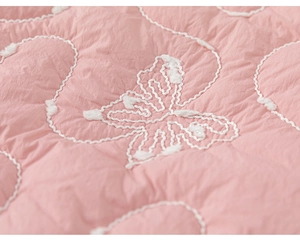 Dettaglio macro del tessuto trapuntato rosa con elegante ricamo a farfalla bianca