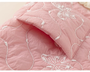Dettaglio della giacca rosa per bambini con ricamo a onde bianche e farfalla applicata