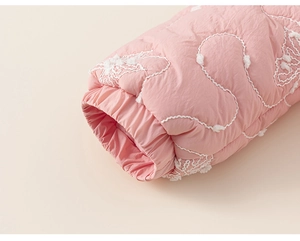 Dettaglio della manica del cappotto trapuntato rosa con ricami floreali e polsini
