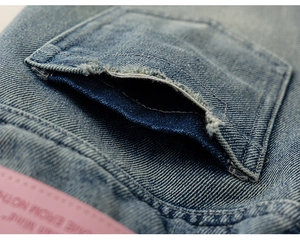 Détail de la poche en jean effet usé avec étiquette rose décorative et coutures de qualité