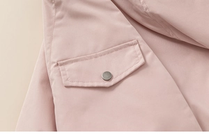 Detail of pink child jacket showing woven fabric pocket and silver snap button