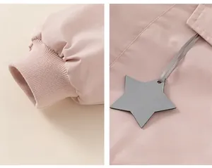 Detail view of pink winter jacket featuring ribbed cuffs and a grey star pendant accessory