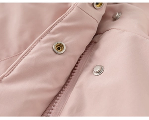 Close-up detail of silver metal buttons and zipper on light pink winter coat