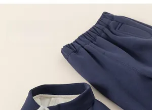 Detail of kids navy knit tracksuit showing elastic waistband and zipped stand collar