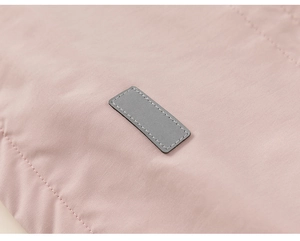 Close-up of pink winter coat fabric featuring a grey rectangular patch with neat stitching