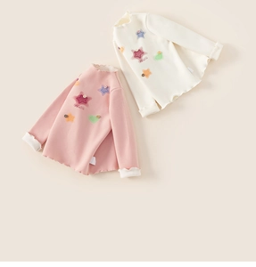 Close-up of pink and beige kids thermal shirts with ruffled edges and star patches