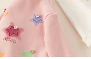 Close-up of pink fleece girl's sweatshirt featuring colorful star prints and button details